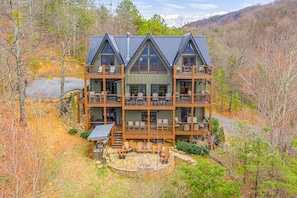 A multi-story cabin with a balcony, outdoor seating, and a stone fireplace. - 50 Mile View Lodge - Your Ultimate Smoky Mountain Retreat (Sevierville)