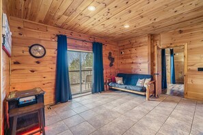 Ein Holzblockhaus-Interieur mit einer Couch, einer Uhr und einem kleinen Tisch mit einer Spielkonsole.