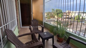 A balcony with a view of the city, furnished with wooden chairs and a small table. - Estudio With Bed, Tv, Ac, Kitchen, Refri and Bacony. (Santo Domingo)