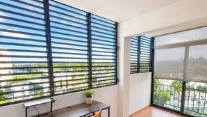 En balkon med et skrivebord, stol og en potteplante.