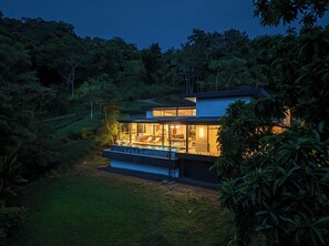Ein modernes Haus mit Swimmingpool, umgeben von üppiger Bepflanzung.