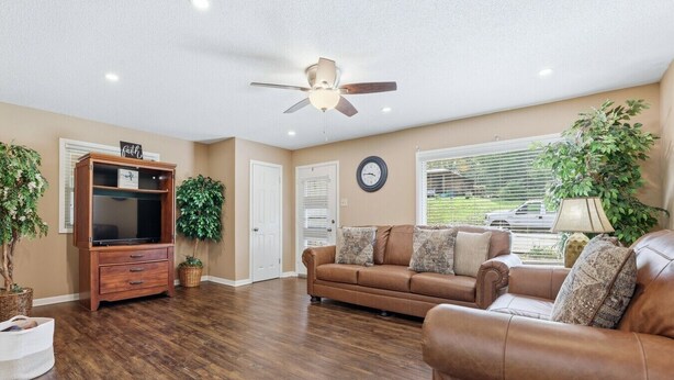 A living room with a brown leather sofa, a wooden entertainment center, and a ceiling fan.