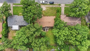 An aerial view of a residential area with houses, trees, and a road.