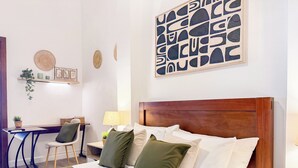 Een keurig ingerichte hotelkamer met een houten hoofdbord, een bureau met stoel, een lamp en een muur met abstracte kunst.