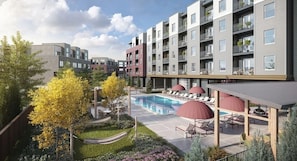 Un immeuble d’appartements moderne doté d’une piscine, d’un espace extérieur aménagé et de balcons.