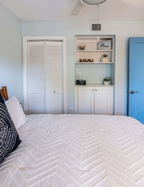 A bedroom with a bed, a wardrobe, a shelf unit, and a blue door. - Sol & Sea Escape Ocean Pointe 1 BR 1BA 1204 (Tavernier)