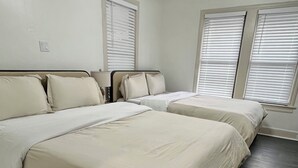 Un dormitorio con dos camas, un ventilador de techo y ventanas con persianas.
