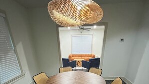 Un comedor con una mesa redonda, seis sillas, un ventilador de techo y un tapete estampado.