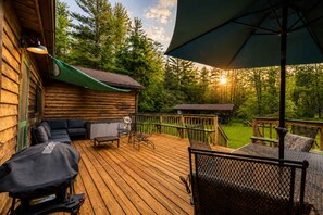 A wooden deck with outdoor furniture, a barbecue grill, and a covered area with a table and chairs.