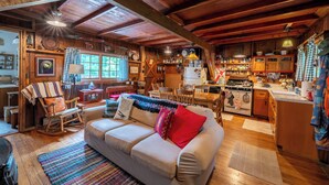 Un interior de cabaña acogedor con zona de comedor de madera, sofá y cocina.