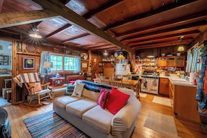 A cozy cabin interior with a wooden dining area, a sofa, and a kitchen.