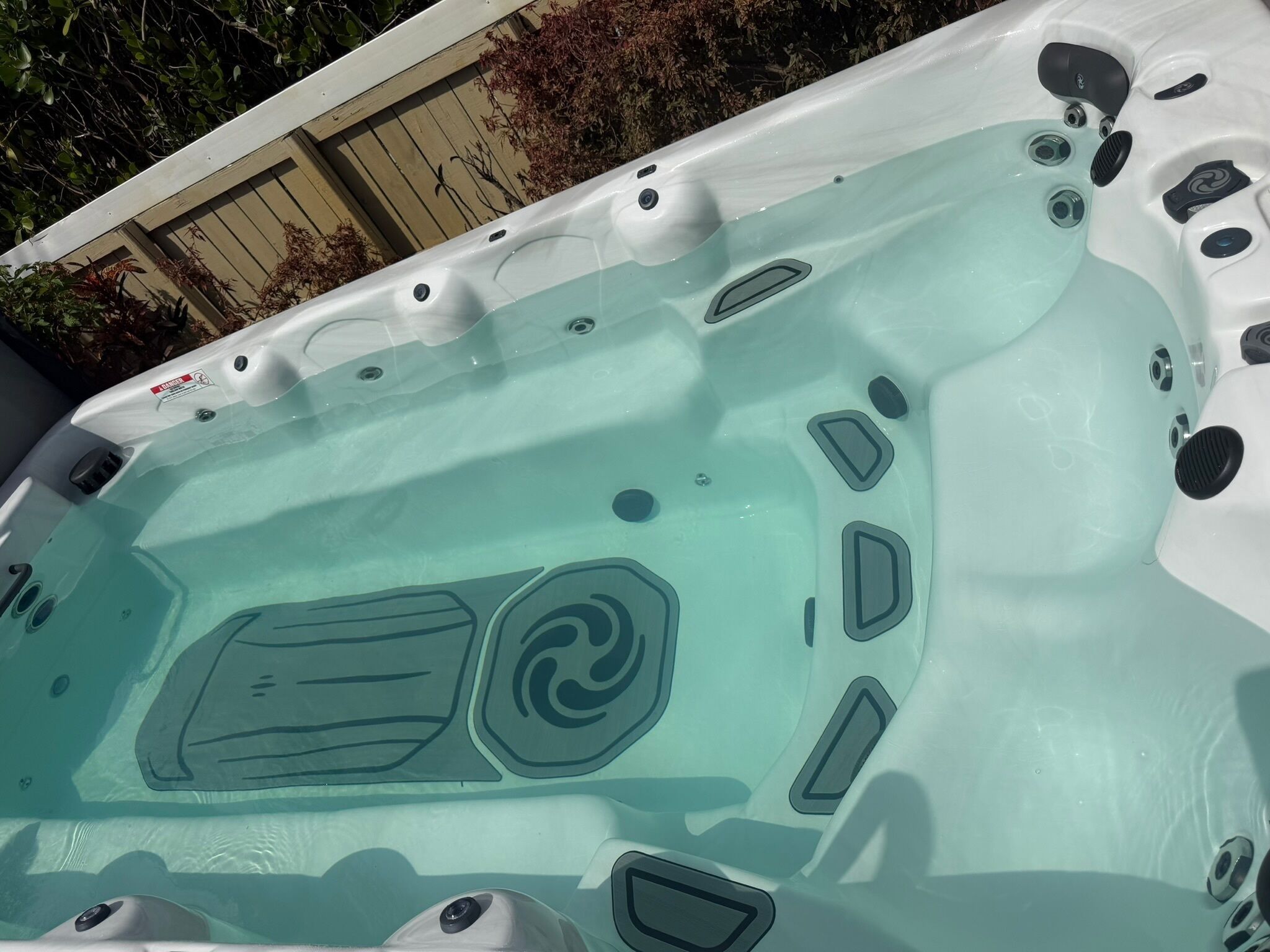 Een jacuzzi met whirlpool functie, meerdere jets en een veiligheidswaarschuwing.