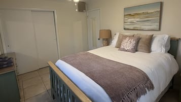 A bedroom with a bed, a nightstand, a lamp, a painting, and a wardrobe.