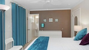 Ein Schlafzimmer mit Bett, einer Bank, einem Spiegel und einer Tür.