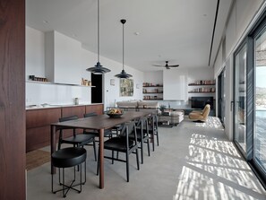 Ein modernes Interieur mit Essbereich, Küche und Wohnbereich, inklusive großem Fenster und Deckenventilatoren.