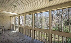 Eine überdachte Veranda mit Blick auf einen Wald.