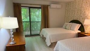 Een hotelkamer met twee bedden, een houten bureau, een lamp en een raam met gordijnen.
