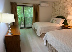 A hotel room with two beds, a wooden desk, a lamp, and a window with curtains. - Lake Fairfield Getaway with Resort Amenities (Sapphire)