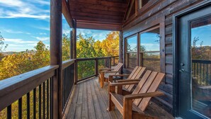 A wooden deck with outdoor seating and a glass door leading to a covered area. - Bears Haven Lodge (Sevierville)