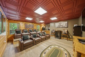 A log cabin interior with a leather sofa, wooden walls, and a ceiling with recessed lighting. - Bears Haven Lodge (Sevierville)