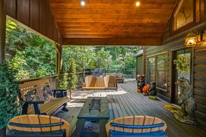 A wooden deck with outdoor seating, a swing, and decorative bear statues. - Bears Haven Lodge (Sevierville)