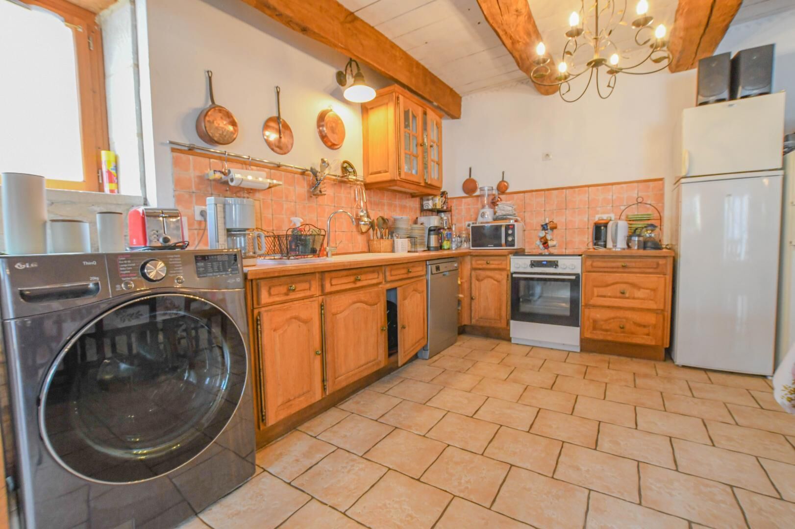 A kitchen with a washing machine, oven, and wooden cabinets.
