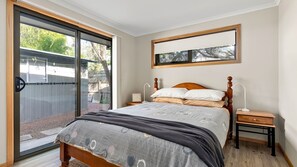 Ein Schlafzimmer mit einem Bett, zwei Nachttischen, einem Fenster und Blick ins Freie.