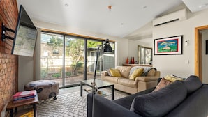 Uma sala de estar moderna com um sofá, uma mesa de centro, uma luminária e uma estante.