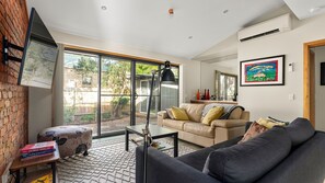 Ein modernes Wohnzimmer mit Sofa, Couchtisch, Lampe und Bücherregal.