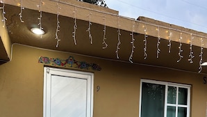 Un edificio con puerta blanca, una ventana y luces colgantes.
