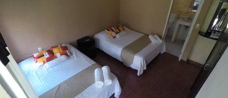 A hotel room with two beds, a bathroom, and a small sitting area.