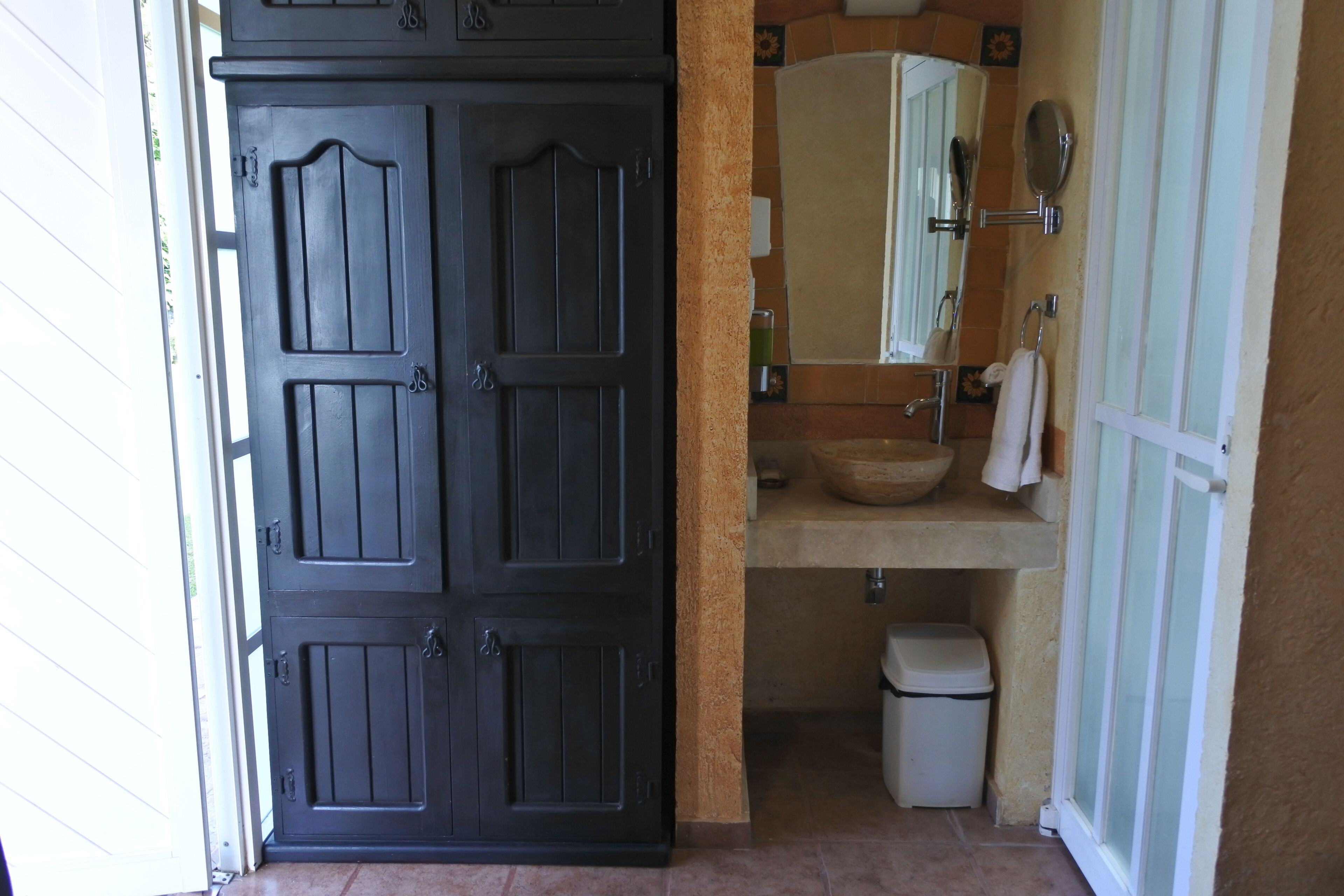 A bathroom with a dark wooden door, a sink, a mirror, and a towel rack.