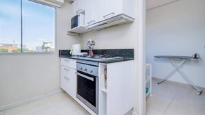 Eine kleine Küche mit Herd, Backofen, Mikrowelle und einem Fenster.