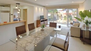 Una sala de estar moderna con una mesa de comedor de vidrio, un sofá y un televisor.