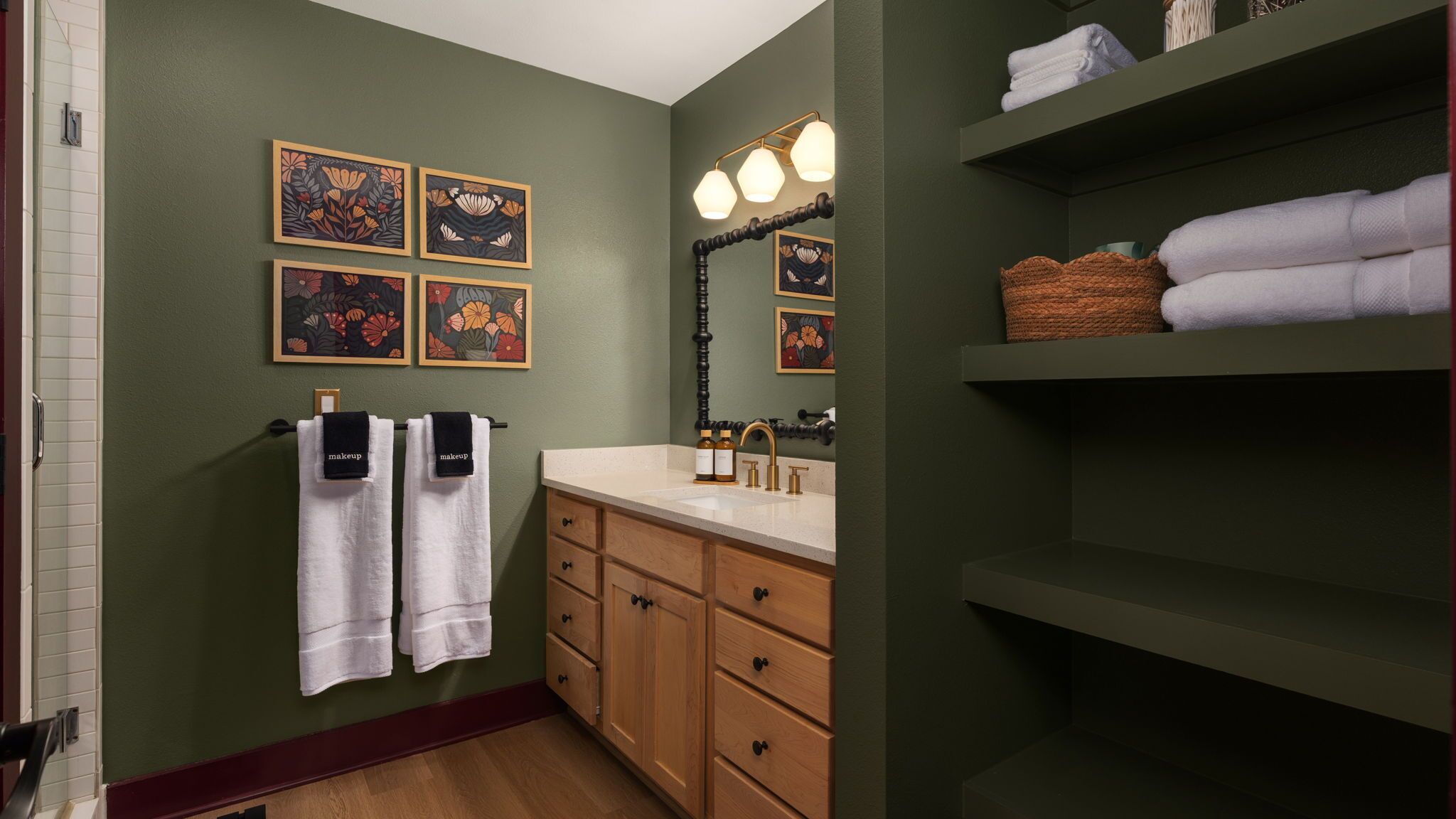 A bathroom with a green wall, a sink with a mirror, and towels hanging on a rack.