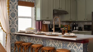 A kitchen with a central island, bar stools, a roll of paper towels, and a coffee maker. - Boutique 4BR Retreat w/Swim Spa • Sauna • Fire Pit (Georgetown)