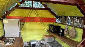 Una cocina compacta con estufa a gas, microondas, cafetera y pileta.