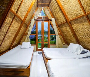 Ein quadratischer Dachraum mit zwei Betten, Holzbalken und Blick durch eine Tür.