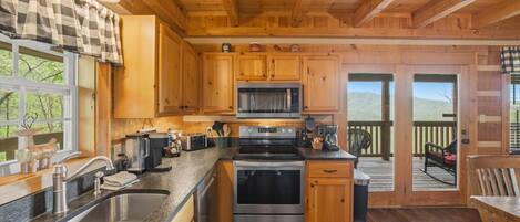 A wooden cabin kitchen with a sink, stove, microwave, and wooden cabinets.