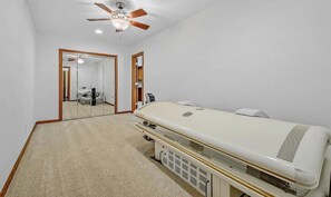 Ein Schlafzimmer mit einem großen Bett, einem Deckenventilator, einem Spiegel und einem Teppichboden.
