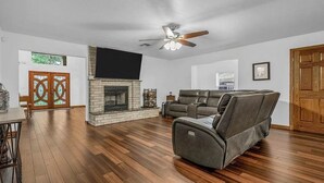 A living room with a fireplace, leather sofa, and a ceiling fan. - Blue Oasis (College Station)