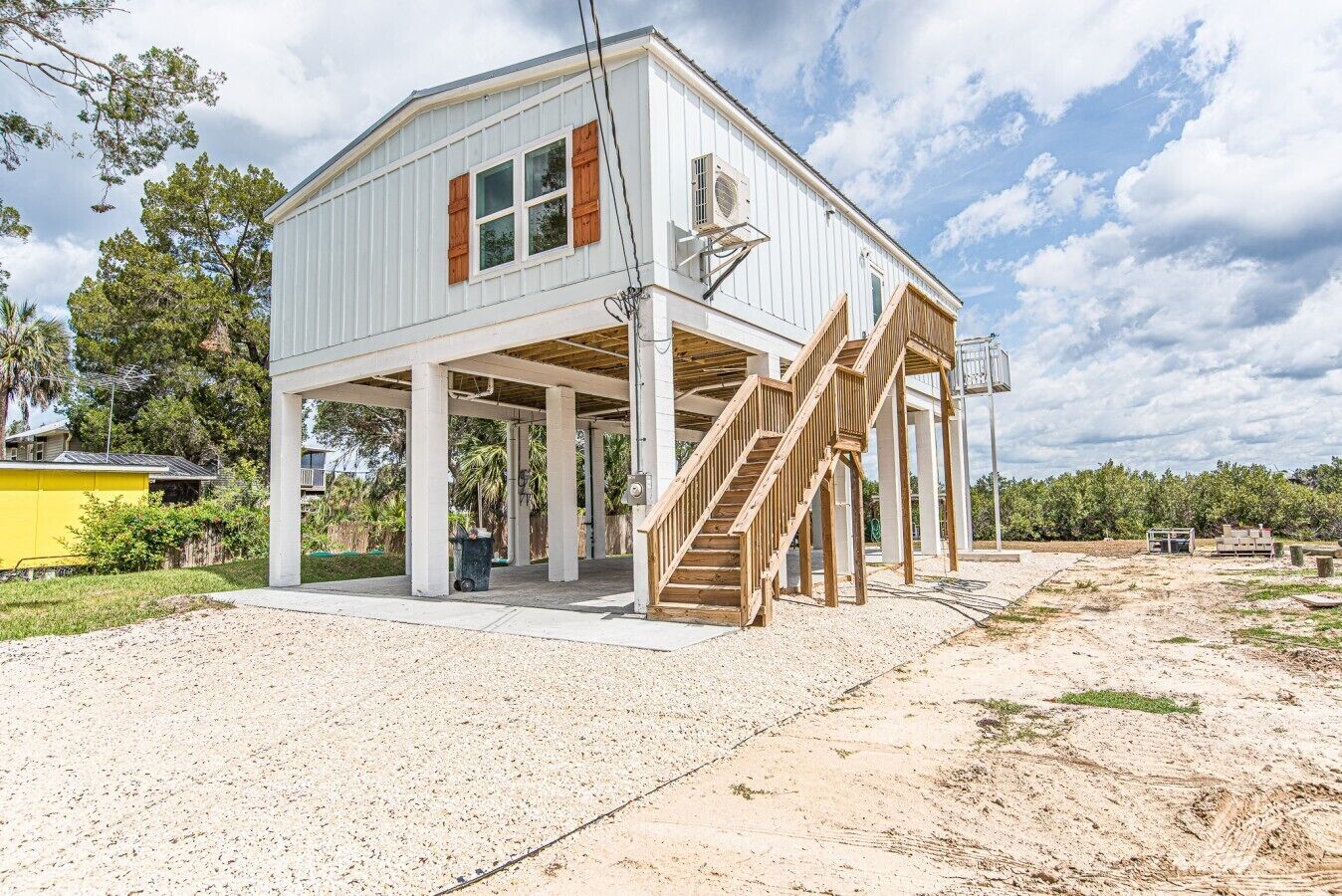 A two-story house with a covered porch, a staircase, and an air conditioning unit.