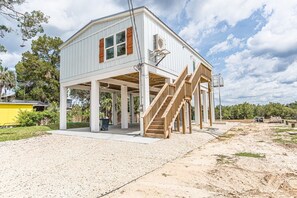 A two-story house with a covered porch, a staircase, and an air conditioning unit. - Ozello Trail Sunrise Cottage (Crystal River)