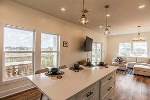 A modern kitchen with a large island, dining area, and a living space with a sofa and TV. - Ozello Trail Sunrise Cottage (Crystal River)