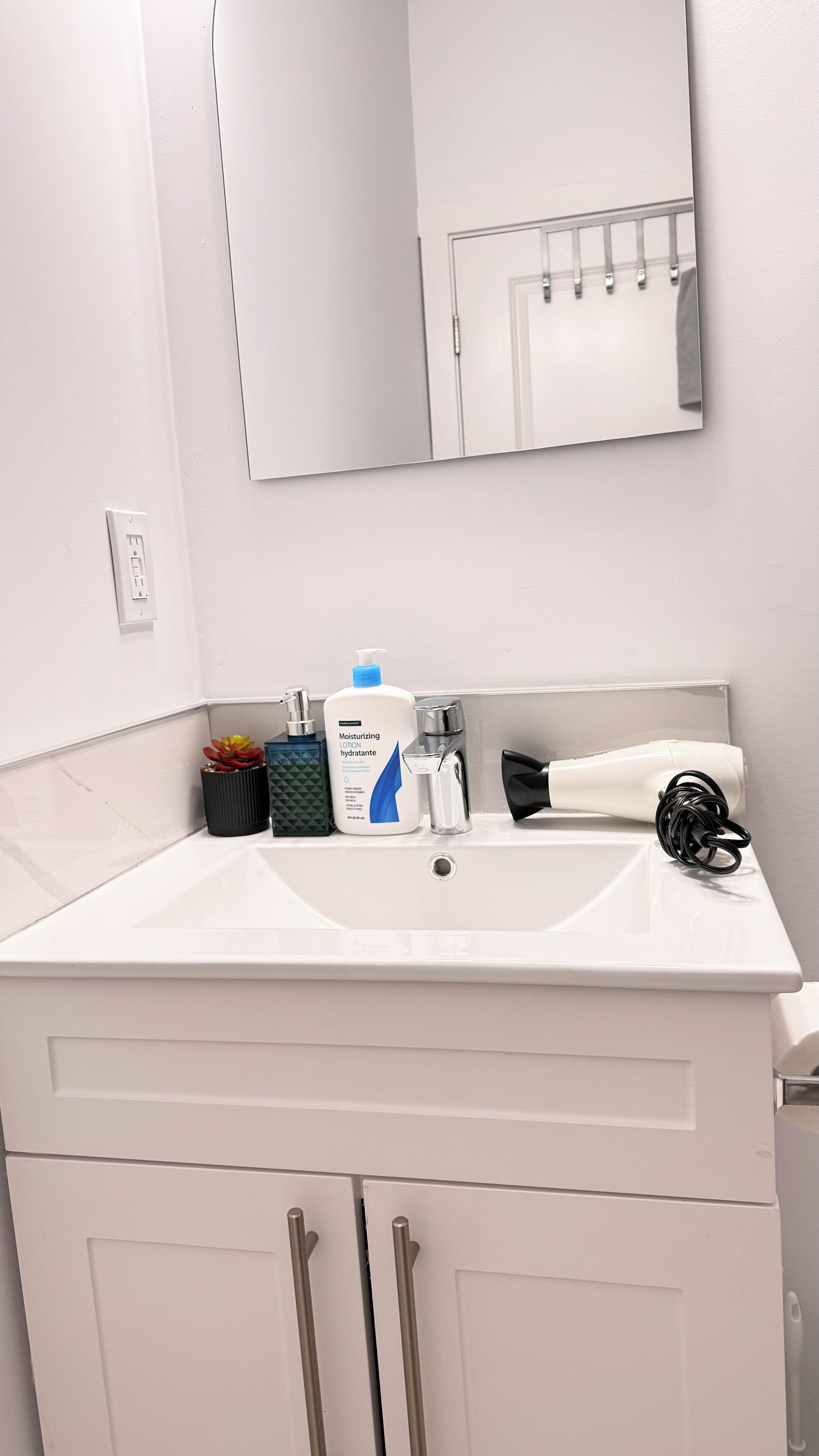 A bathroom with a white sink, a mirror, and a cabinet with drawers.