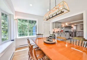 Una cocina moderna con armarios grises, una isla grande y una zona de comedor con mesa y sillas de madera.