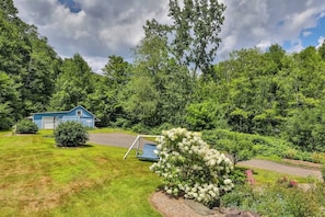 A blue building with a garage, surrounded by lush greenery and trees.