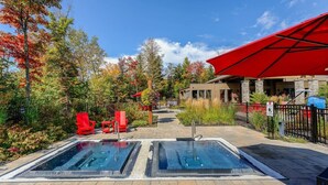 Ein Poolbereich mit zwei Whirlpools, roten Liegestühlen und einer überdachten Terrasse.