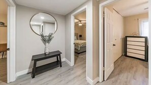 Un passadís amb un mirall, una banca i una porta que condueix a una habitació.