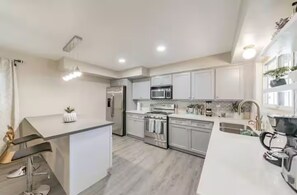Una cocina moderna con armarios blancos, electrodomésticos de acero inoxidable y una zona de bar.